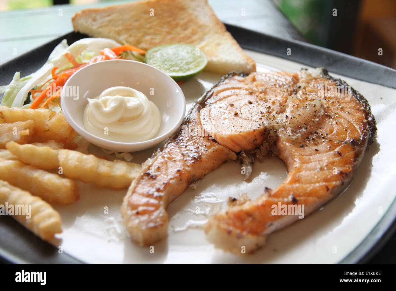 Salmone alla griglia bistecca con patate fritte e toast sul tavolo nel ristorante. Foto Stock