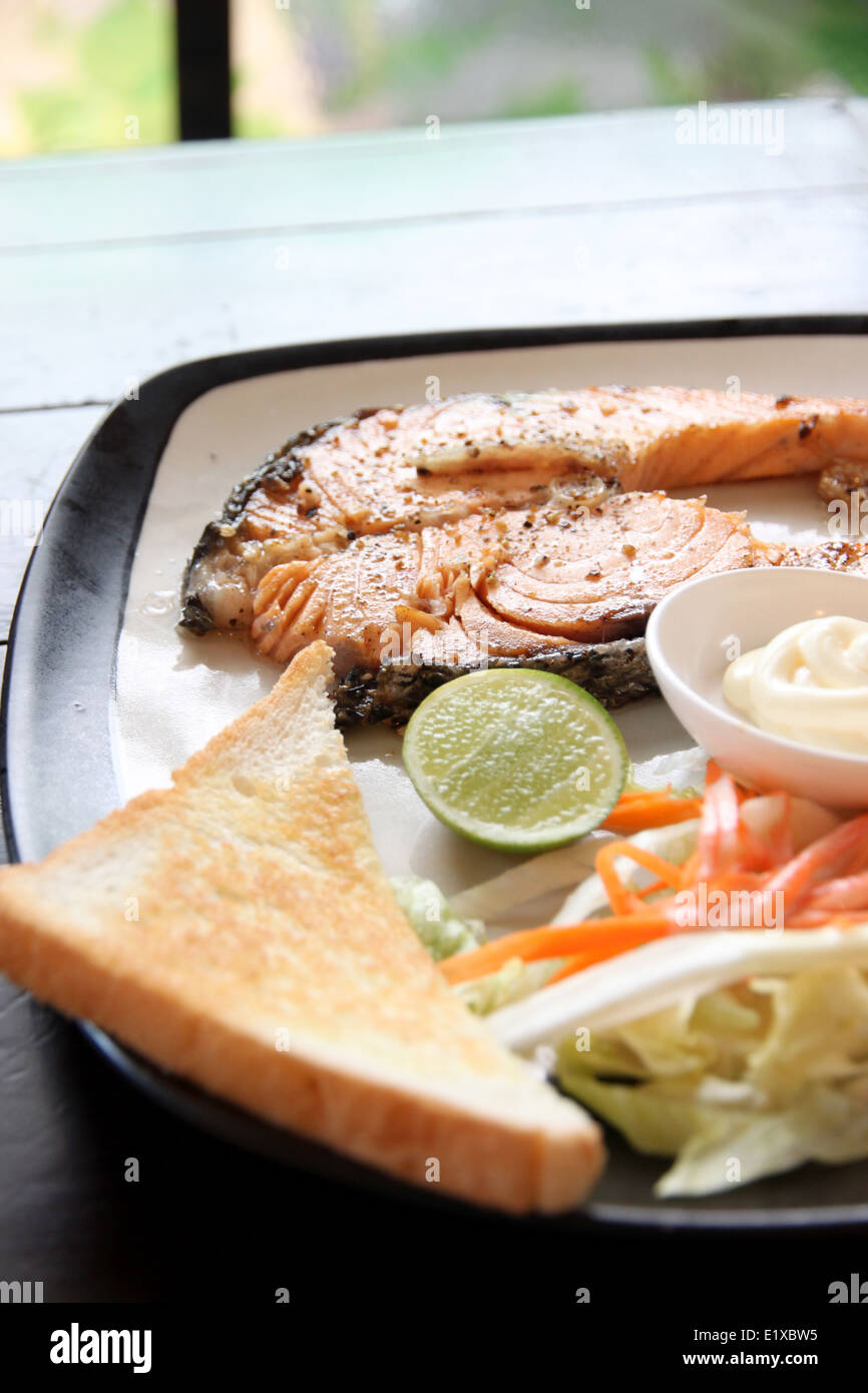 Salmone alla griglia bistecca con patate fritte e toast sul tavolo nel ristorante. Foto Stock