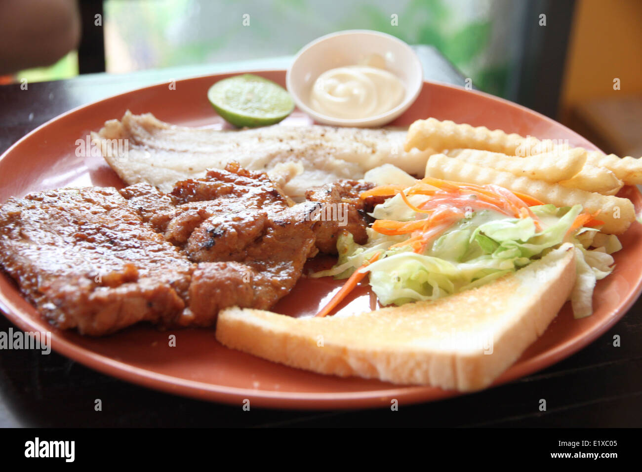 Carne di maiale alla griglia bistecca con patate fritte e toast sul tavolo nel ristorante. Foto Stock