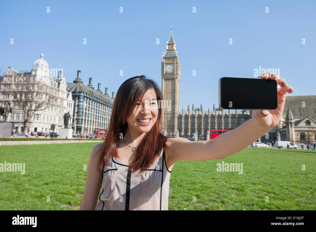 Giovane donna prendendo ritratto di auto attraverso smart phone contro il Big Ben a Londra, Inghilterra, Regno Unito Foto Stock