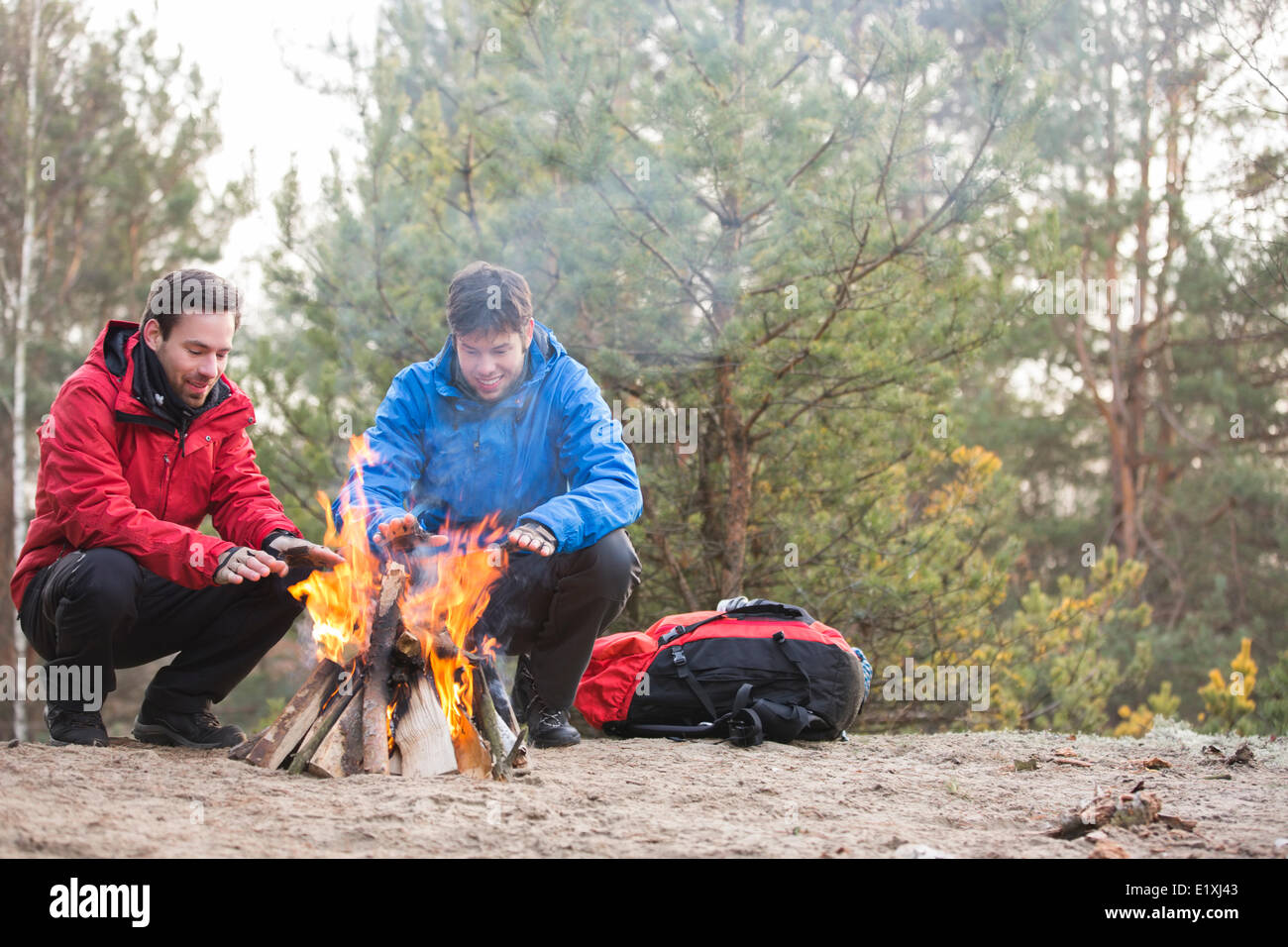 Backpackers maschio mani di riscaldamento a fuoco nella foresta Foto Stock