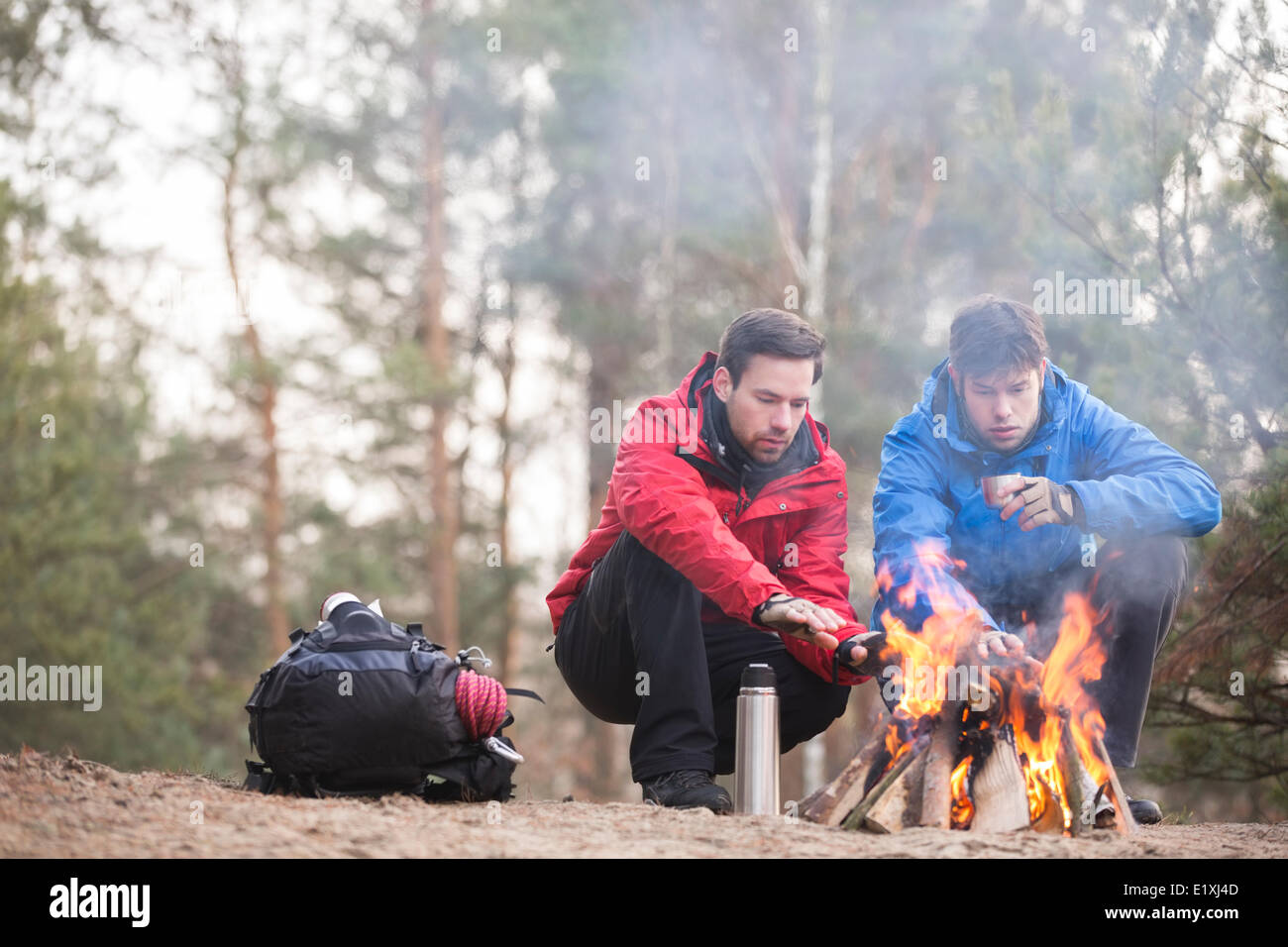 Gli escursionisti maschio mani di riscaldamento a fuoco nella foresta Foto Stock