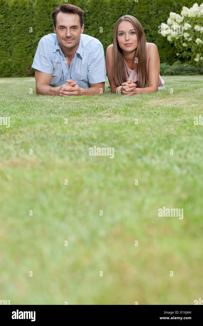 Ritratto di giovane coppia affiancati su erba nel parco Foto Stock