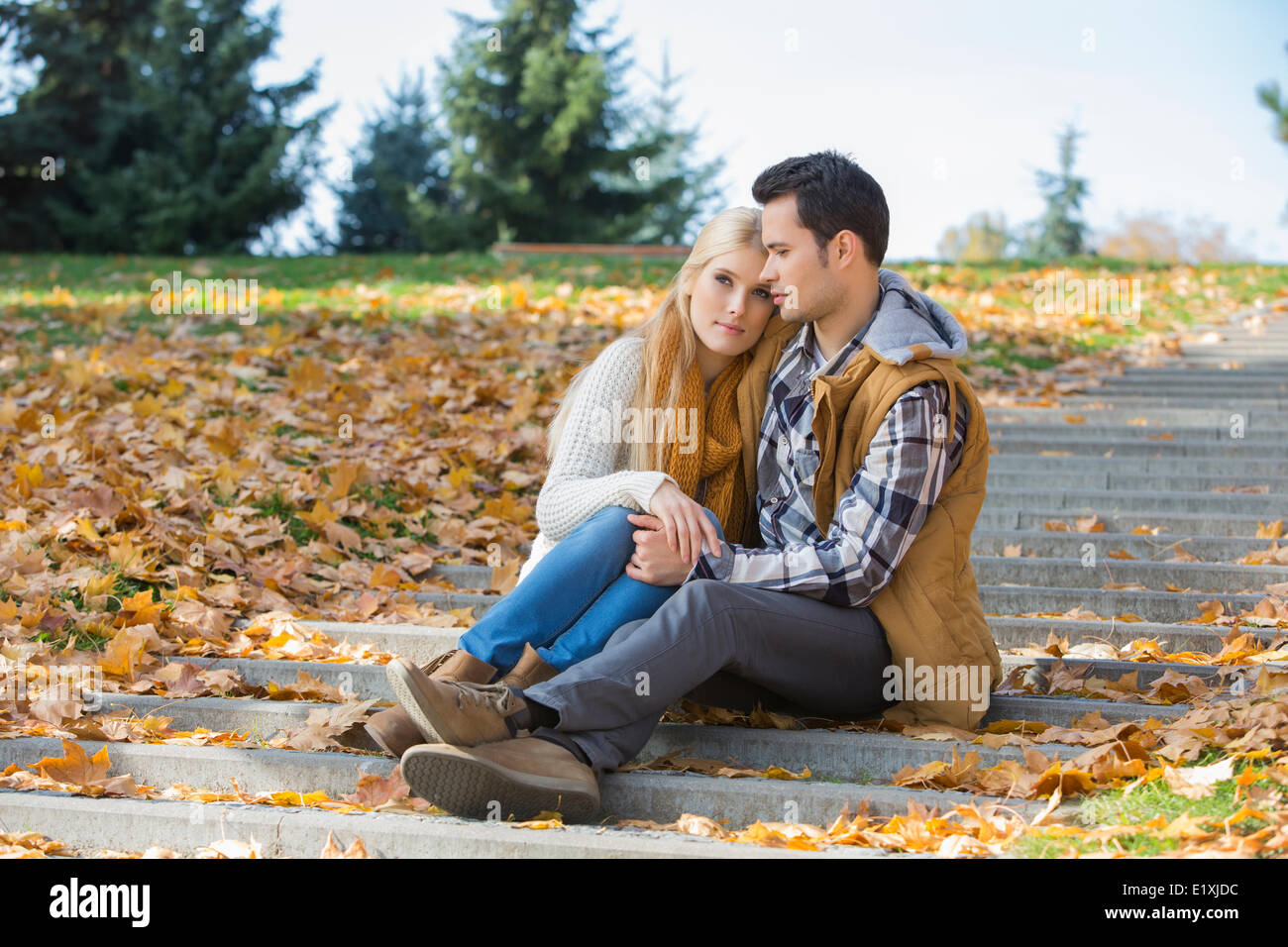 Amare giovane seduti insieme su passi nel parco durante l'autunno Foto Stock
