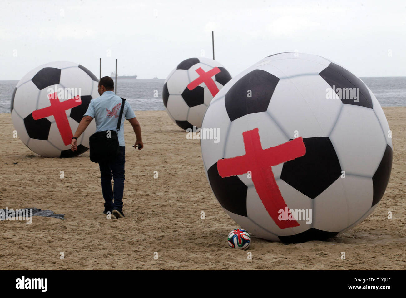 Rio de Janeiro, Brasile. Decimo Giugno, 2014. La ONG Rio de Paz rende la dimostrazione contro la spesa pubblica per la Coppa del Mondo in sabbie della spiaggia di Copacabana, della zona sud di Rio de Janeiro, Brasile sudorientale, il 10 giugno 2014. Dodici giganteschi palloni da calcio dipinto con le croci rosse che simboleggiano le dodici città ospitante della Coppa del mondo, sono state fissate in sabbie. Credito: dpa picture alliance/Alamy Live News Foto Stock