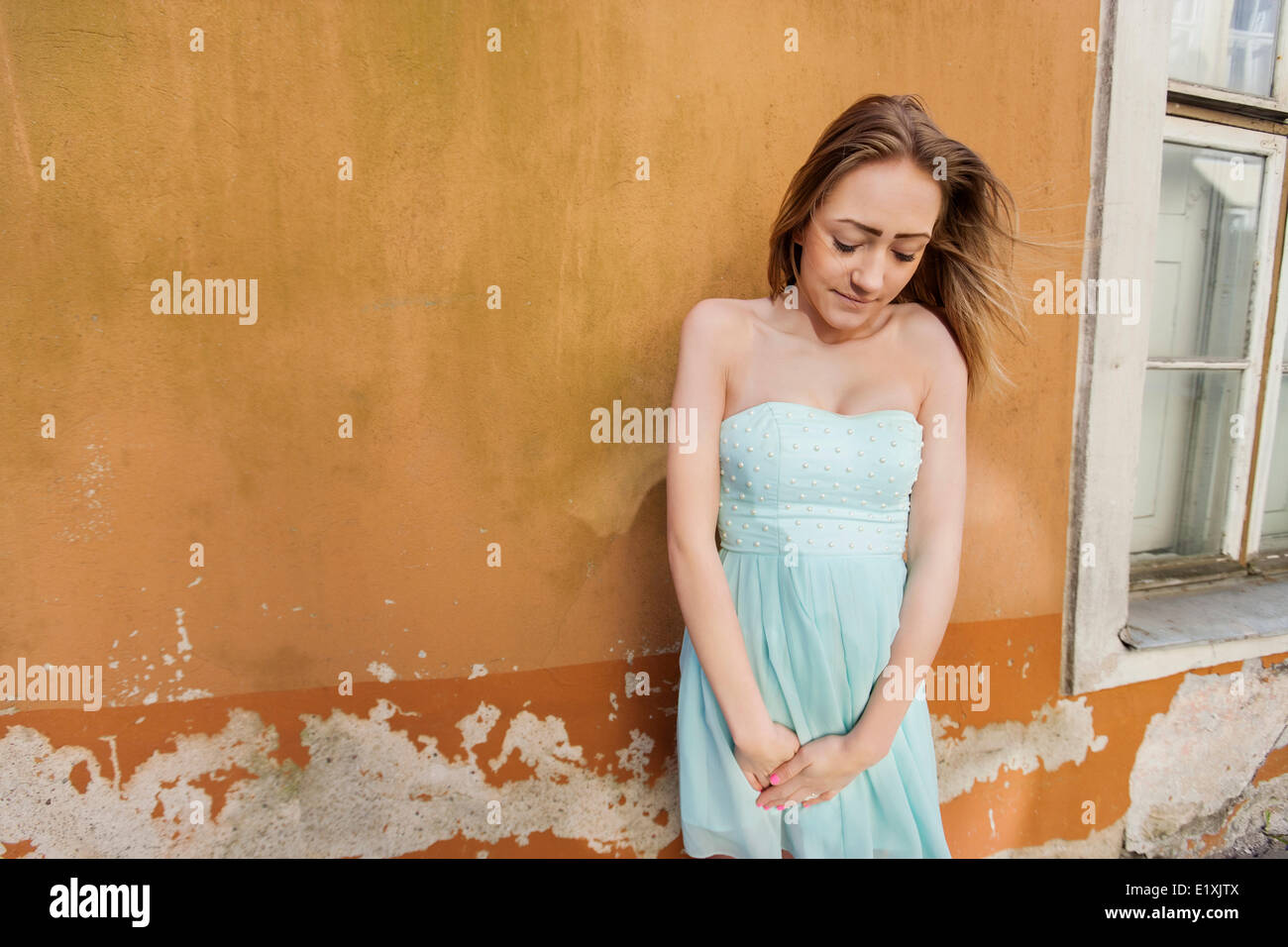 Timida ragazza adolescente in abito di tubo in piedi contro la parete Foto Stock