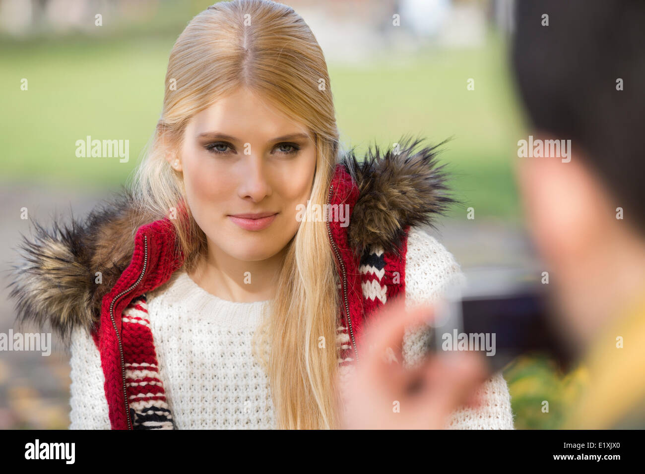 Bella giovane donna fotografata da uomo nel parco Foto Stock