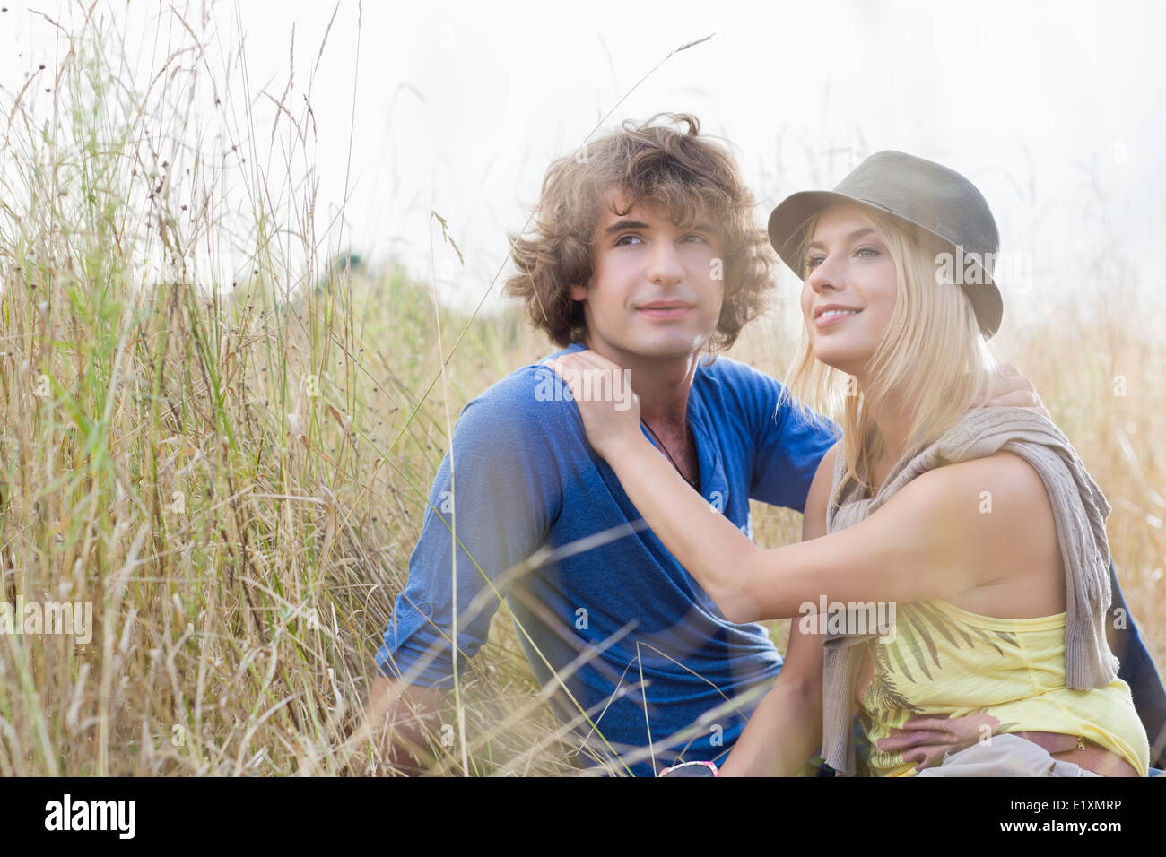 Amare giovane coppia in cerca di distanza mentre sedendo nel campo Foto Stock