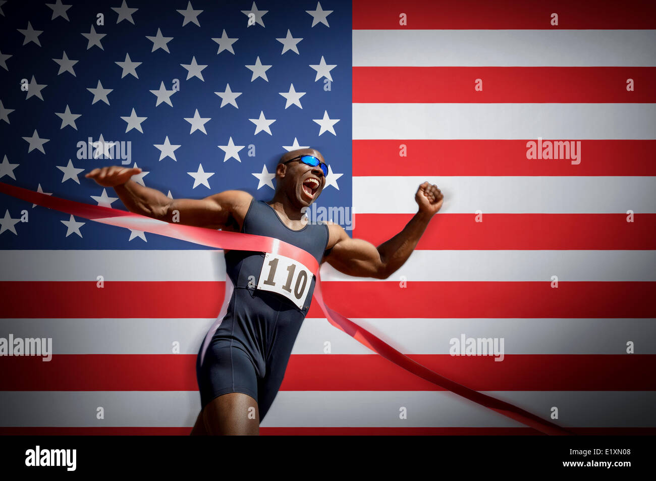 Atleta maschio Attraversamento linea di finitura contro la bandiera americana Foto Stock