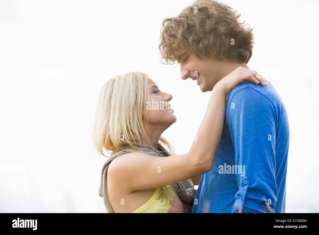 Romantico coppia giovane guardando ogni altro contro il cielo chiaro Foto Stock