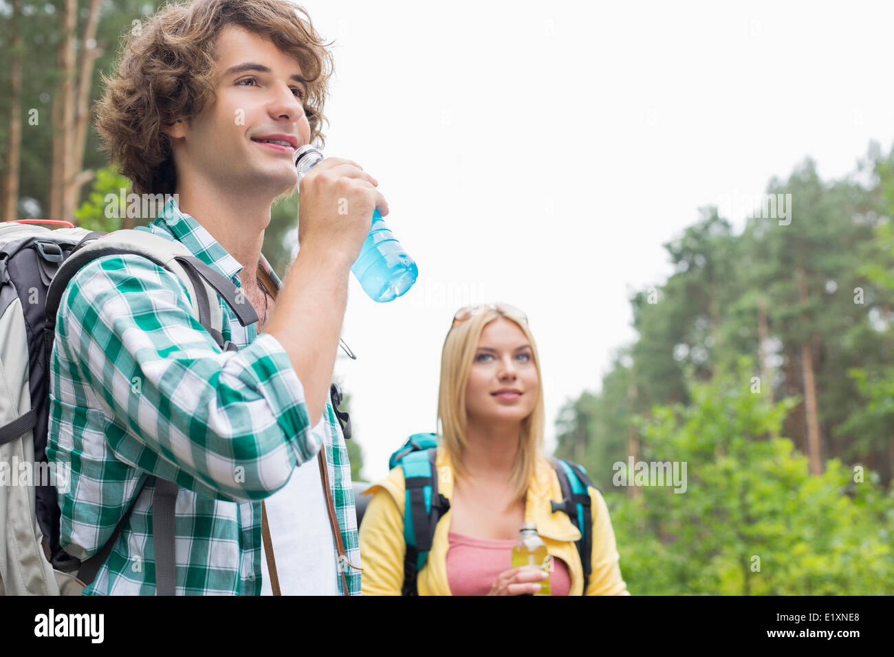 Escursionismo coppia bere bevande energetiche in foresta Foto Stock