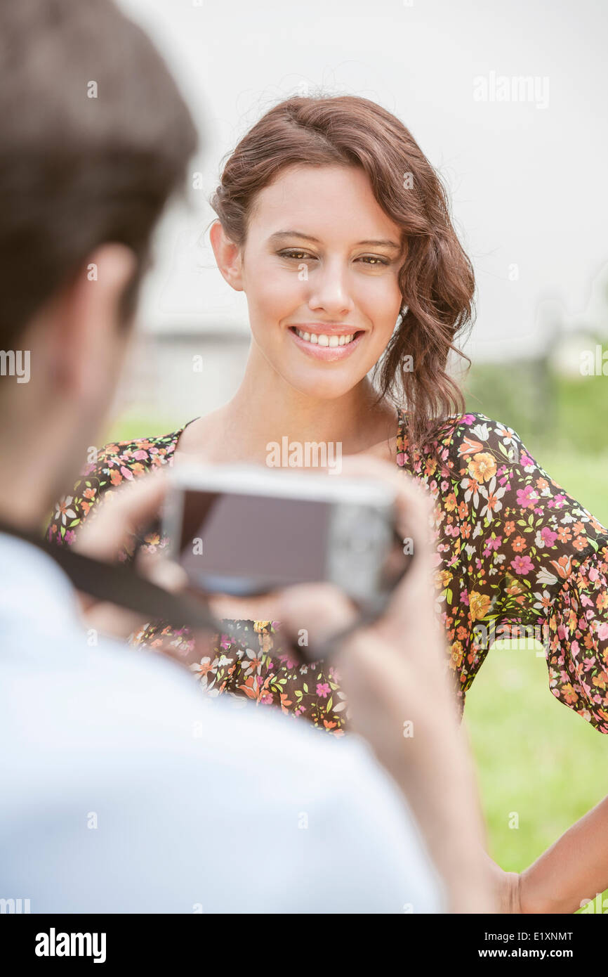 Felice giovane donna fotografata da uomo nel parco Foto Stock