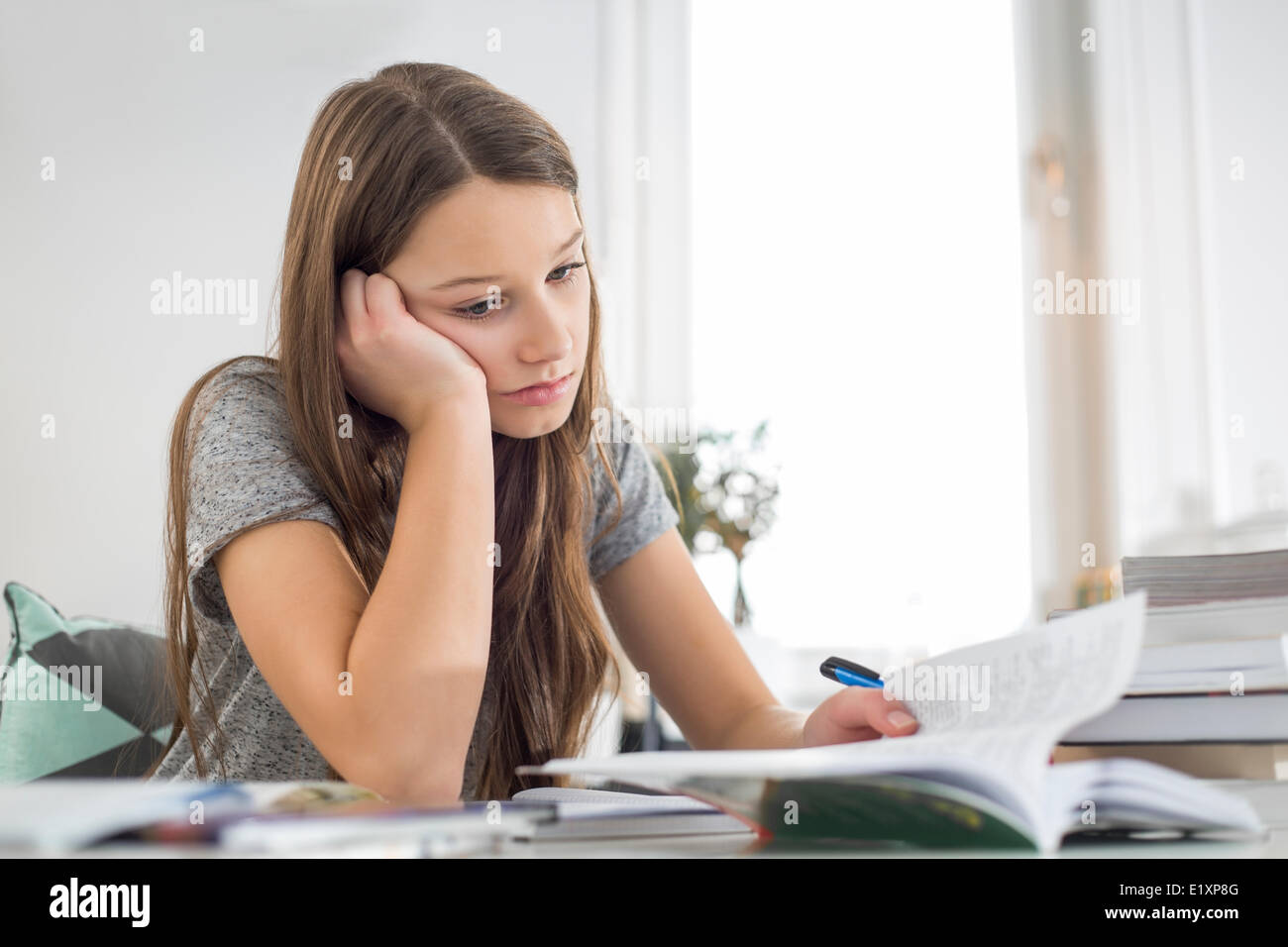 Annoiato ragazza studiare a tavola in casa Foto Stock
