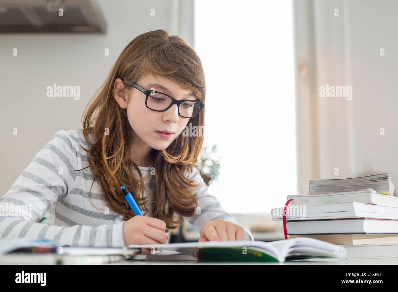 Ragazza adolescente facendo i compiti sul tavolo Foto Stock