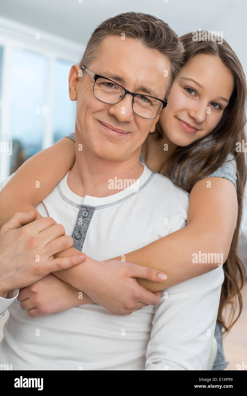 Ritratto di affettuosa ragazza abbracciando il padre da dietro a casa Foto Stock