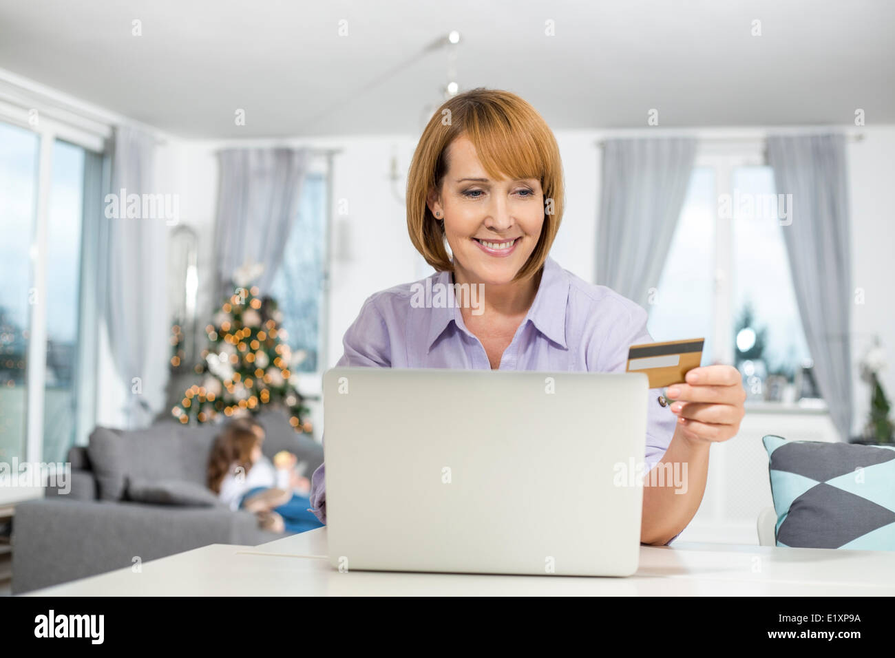 Donna felice shopping online a casa durante il periodo di Natale Foto Stock