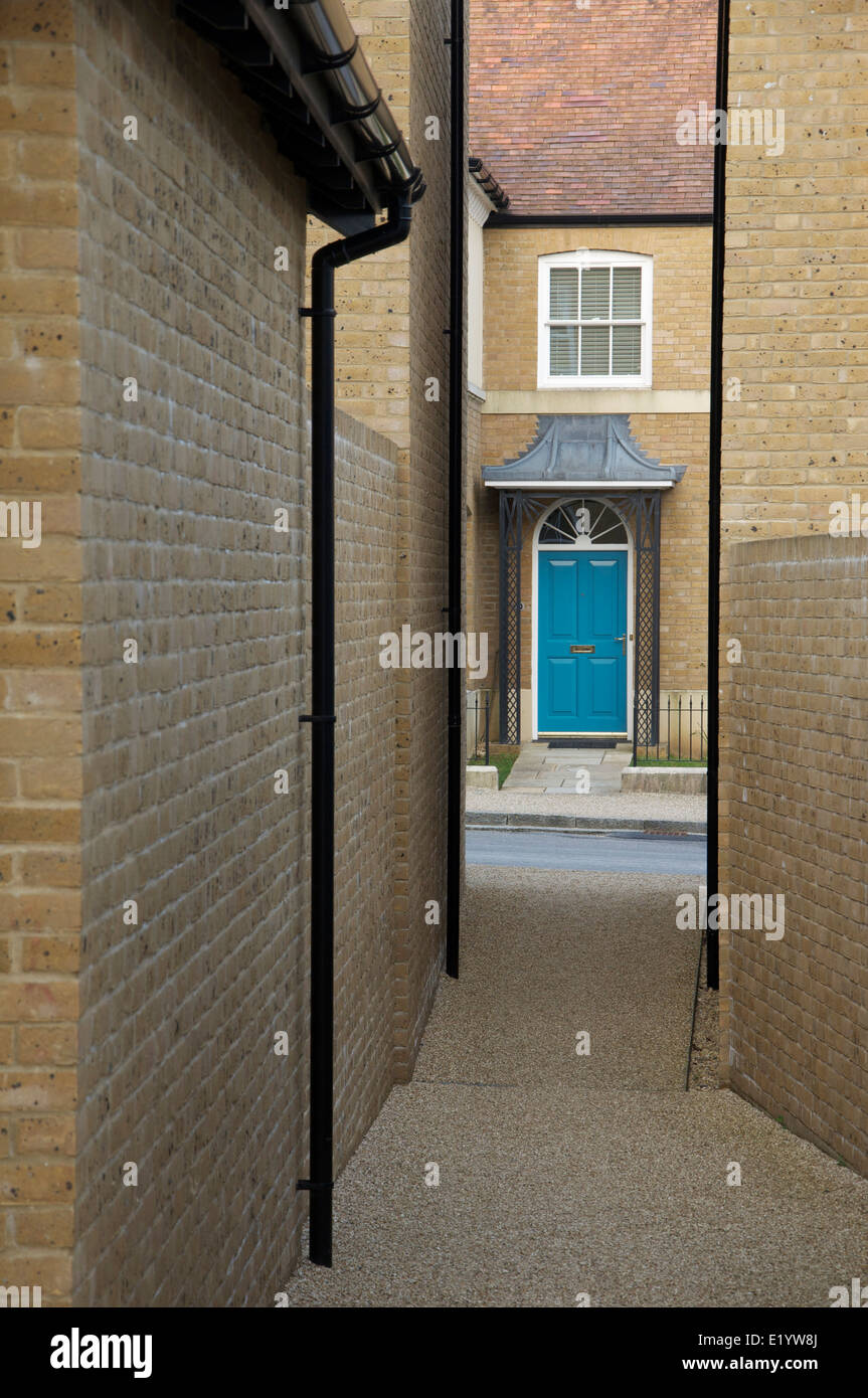 Architettura moderna. Uno stretto vicolo tra due case si apre su una strada e i telai della porta anteriore di una casa di fronte a. Poundbury, Dorchester, Regno Unito. Foto Stock