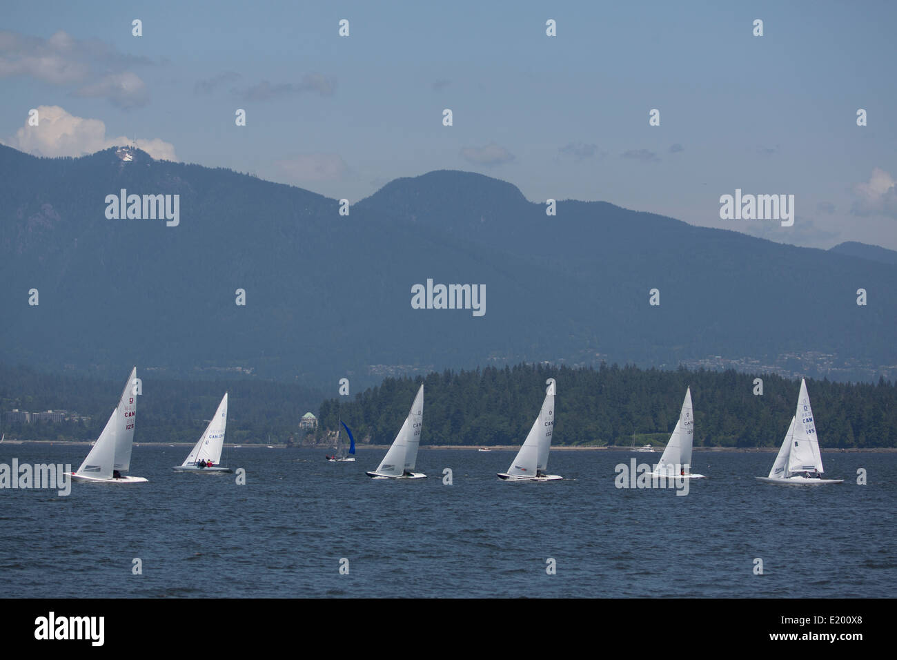 Una linea di sei barche a vela sono visti da Jericho Beach, Vancouver, con le montagne sullo sfondo. Foto Stock