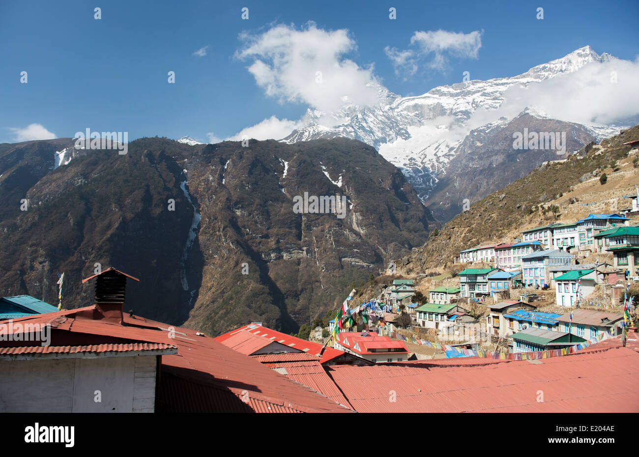 Il Nepal Namche Bazarre. Preghiera bandiere su edifici con le montagne sullo sfondo remoto, Mt Everest Foto Stock