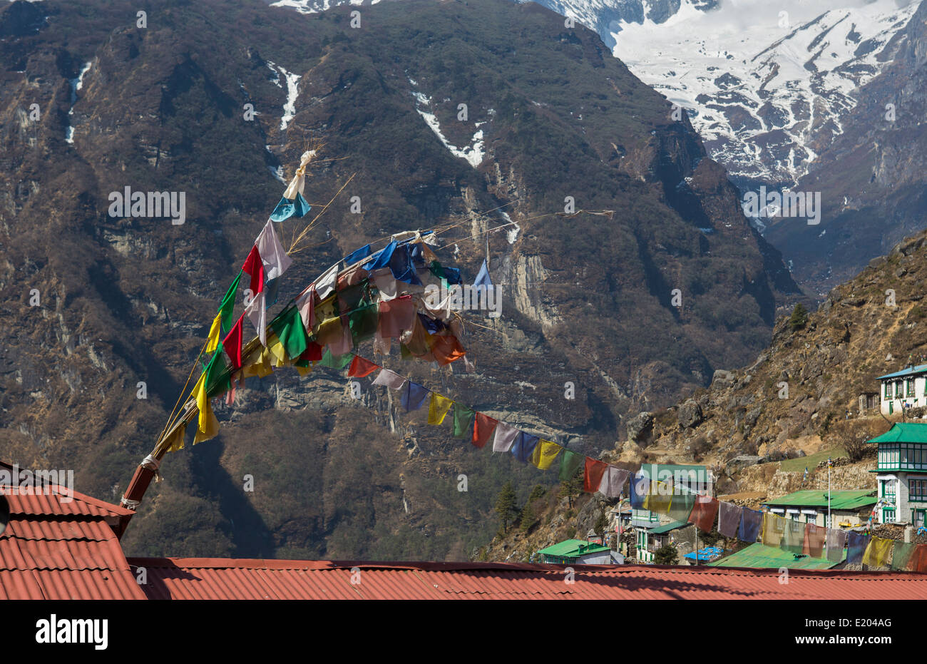 Il Nepal Namche Bazarre. Preghiera bandiere su edifici con le montagne sullo sfondo remoto, Mt Everest Foto Stock