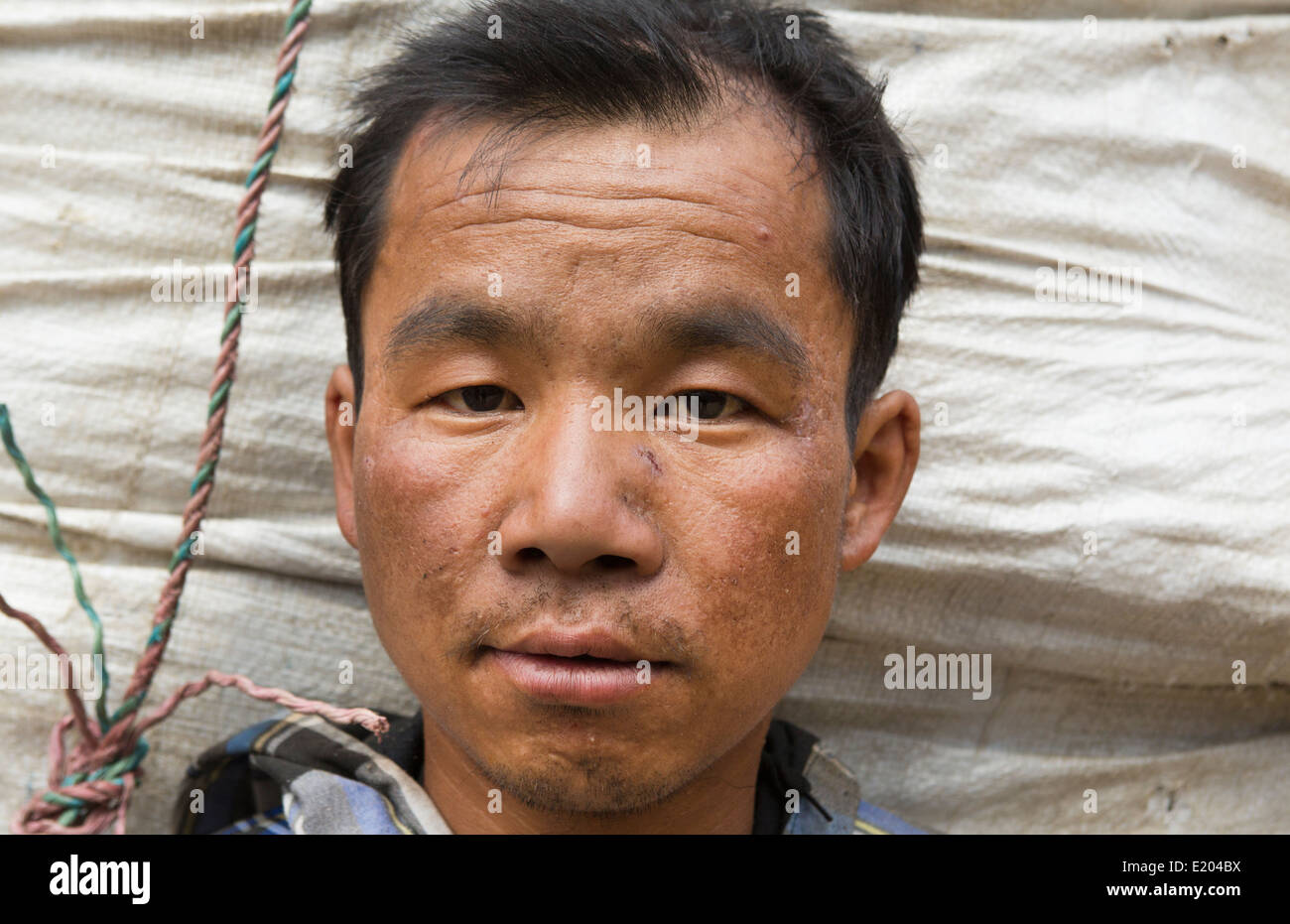 Il Nepal Porter pone per la fotocamera con la testa contro il cestello carico in Thamo, Solukhumburemote, Mt Everest, Himalaya 81 Foto Stock