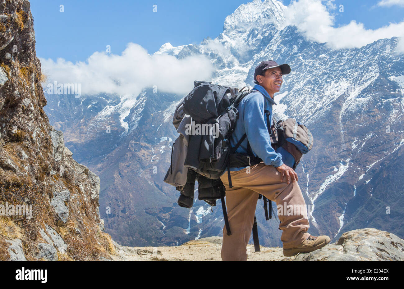 Il Nepal. Il Trekking guida pone con i suoi sacchi e l'Himalayan montagne in distanza. Solukhumbu, remoto, Mt Everest, Foto Stock
