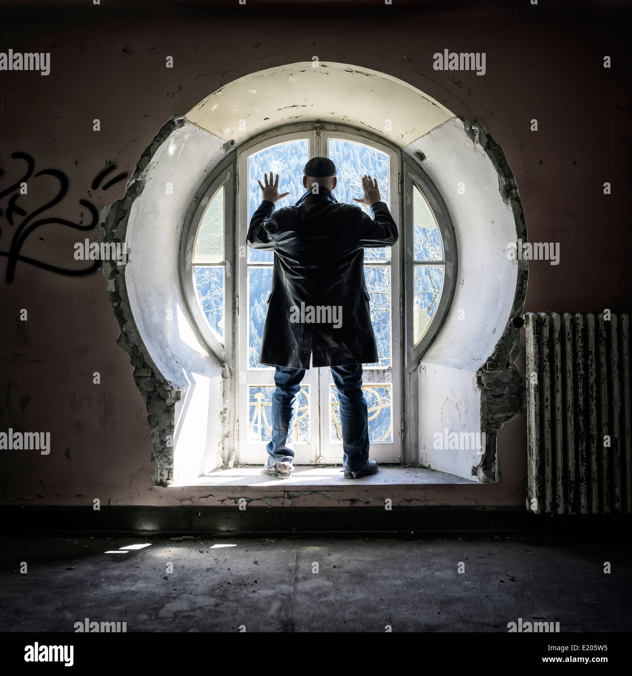 Un uomo di fronte a un vecchio vetro in un edificio abbandonato Foto Stock