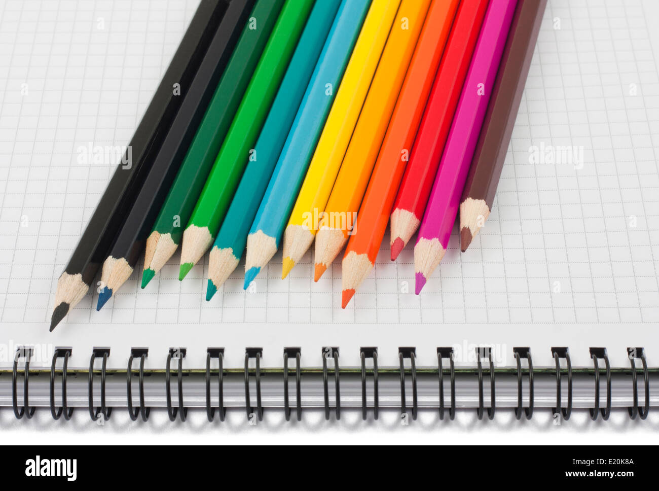 Matite multicolori sul notebook a spirale Foto Stock