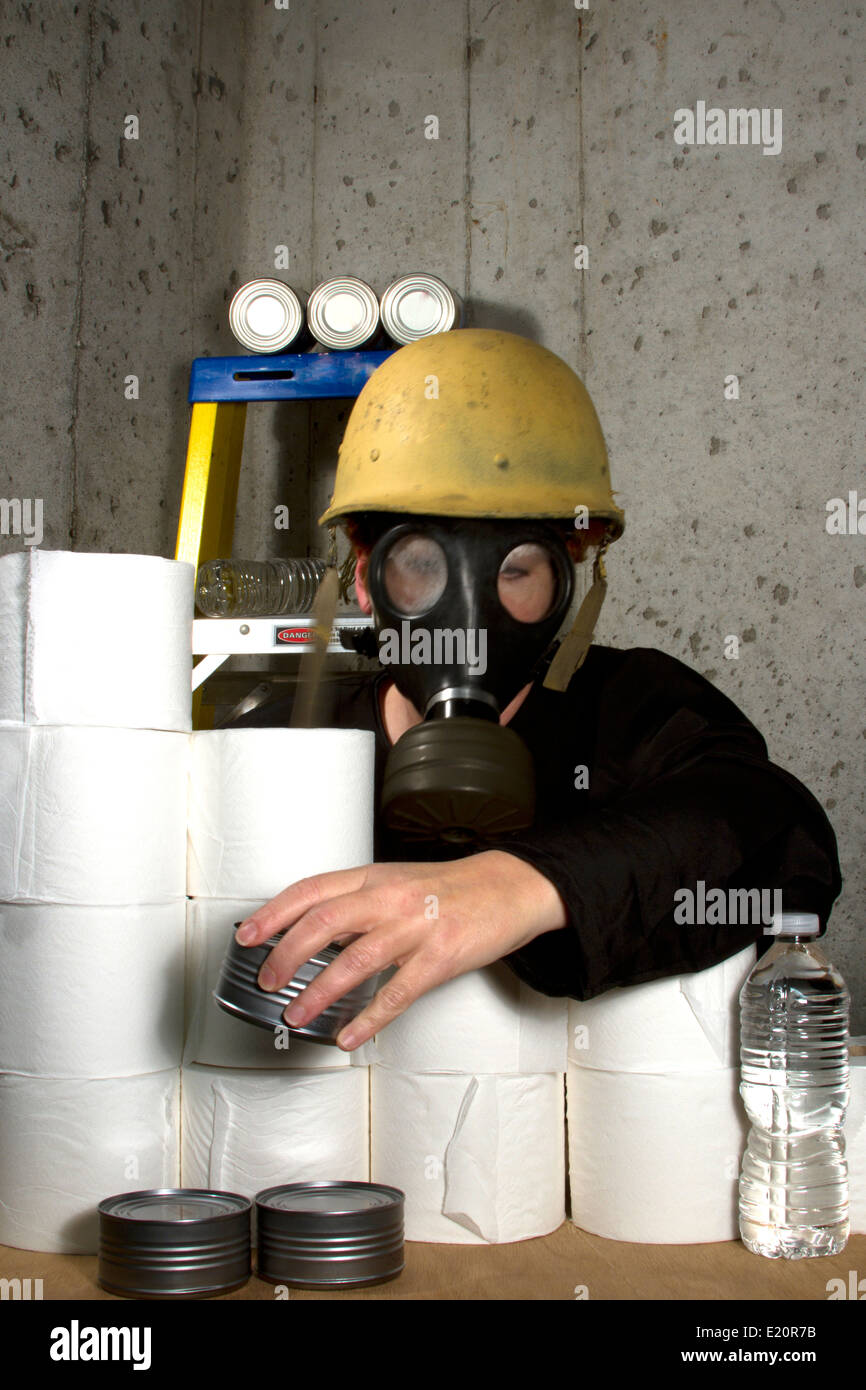Donna vestita in maschera a gas e di elmetto nascondere nel seminterrato con ammassate merci Foto Stock