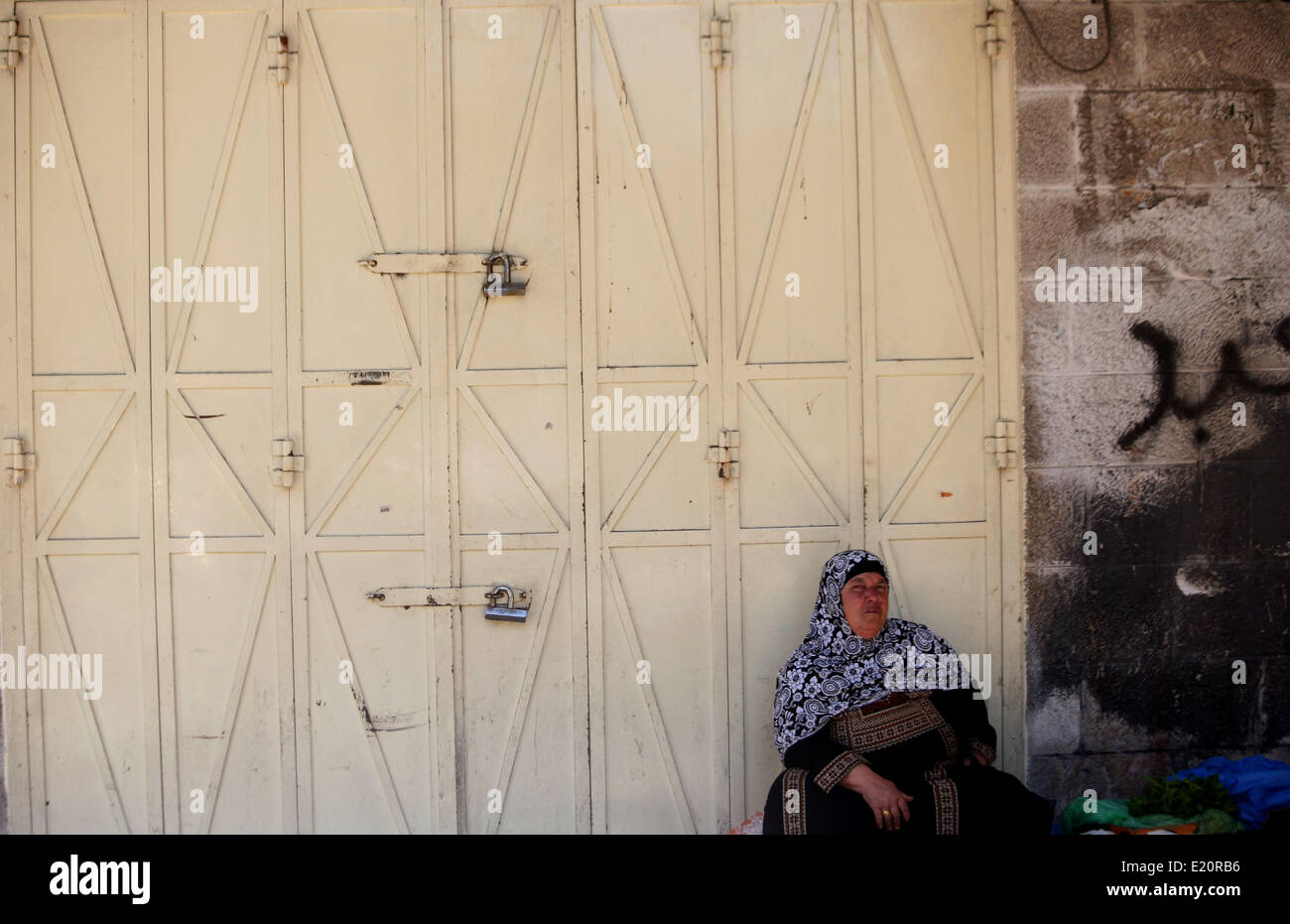 Gerusalemme, Gerusalemme, Territorio palestinese. 12 Giugno, 2014. Una donna Palestinese si siede di fronte a negozi chiusi in Gerusalemme la città vecchia di Giugno 12, 2014. I negozi sono state chiuse a Gerusalemme Est giovedì per mostrare solidarietà con centinaia di prigionieri palestinesi nelle carceri israeliane che hanno aderito a uno sciopero della fame a partire dalla fine di aprile, in segno di protesta su una politica israeliana che consente la detenzione indefinita senza processo © Saeed Qaq APA/images/ZUMAPRESS. Foto Stock