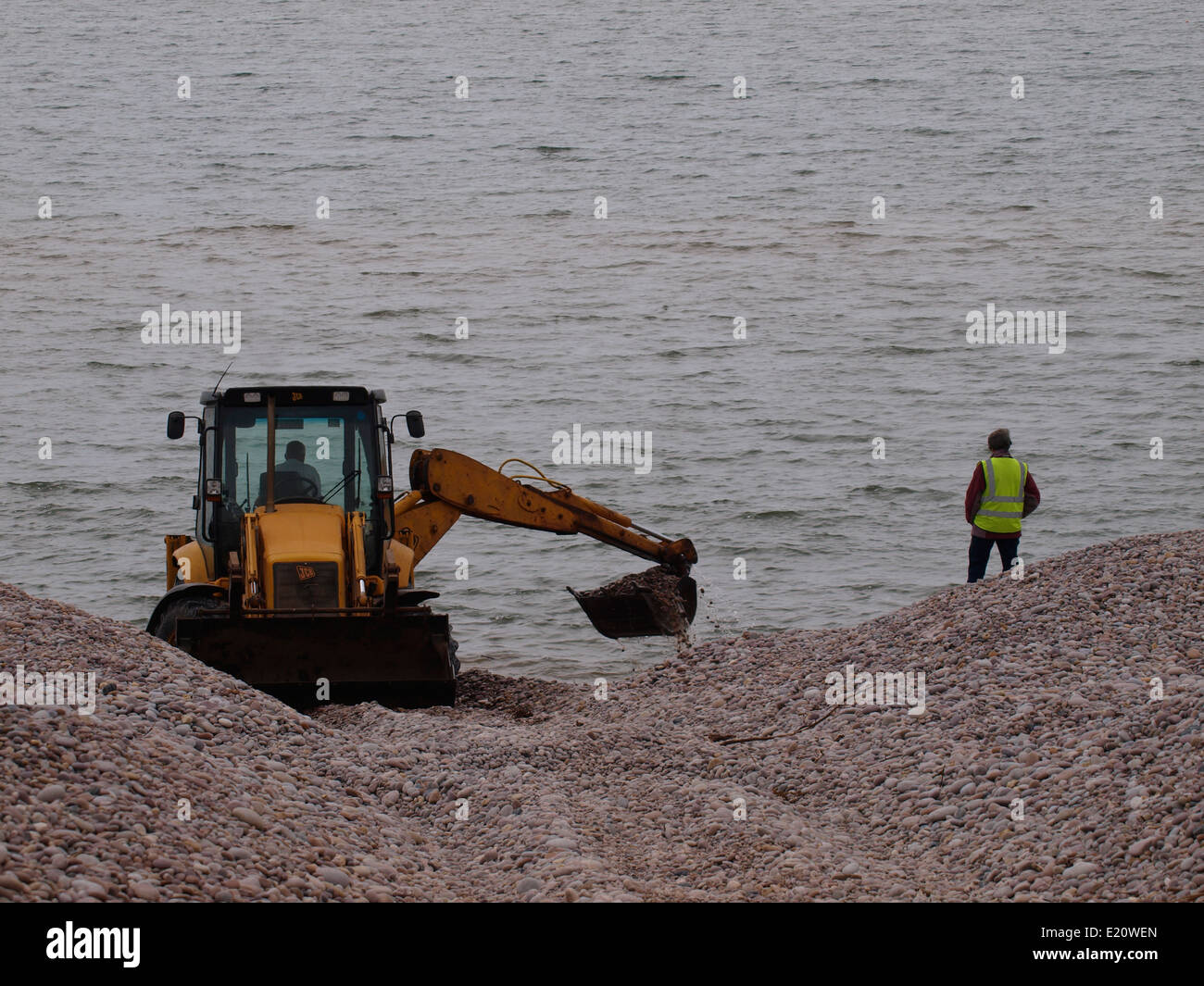 JCB digger spostando i ciottoli sulla spiaggia a Budleigh Salterton, Devon, Regno Unito Foto Stock