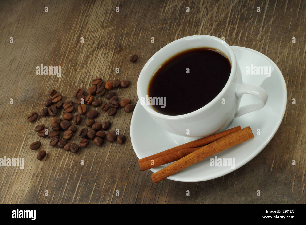Tazza da caffè con fagioli e bastoncini di cannella sul vecchio Sfondo legno close-up Foto Stock