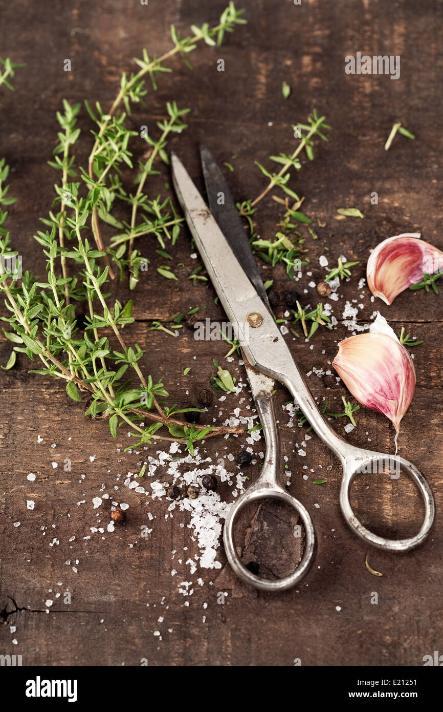 Il timo, aglio e un paio di forbici sul vecchio tavolo da cucina Foto Stock