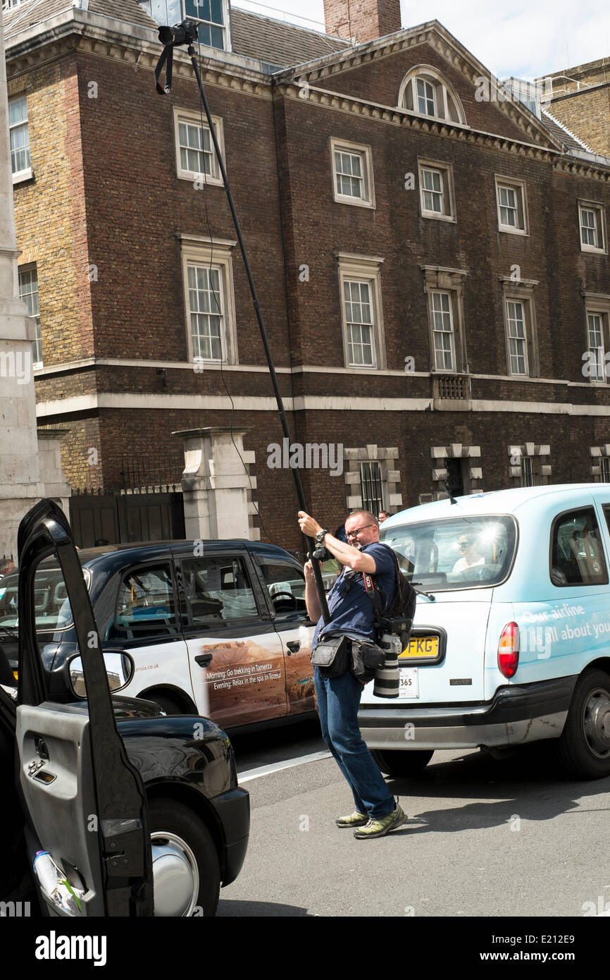 Premere il fotografo al lavoro a Whitehall durante il London Taxi colpire oltre il mobile Uber App. Utilizzando una telecamera su un 5 metro asta comandati dal suo cellulare. Migliaia di London Black Cabs ha portato le parti del centro di Londra a un fermo. Whitehall, Londra centrale, 11 giugno 2014 Foto Stock