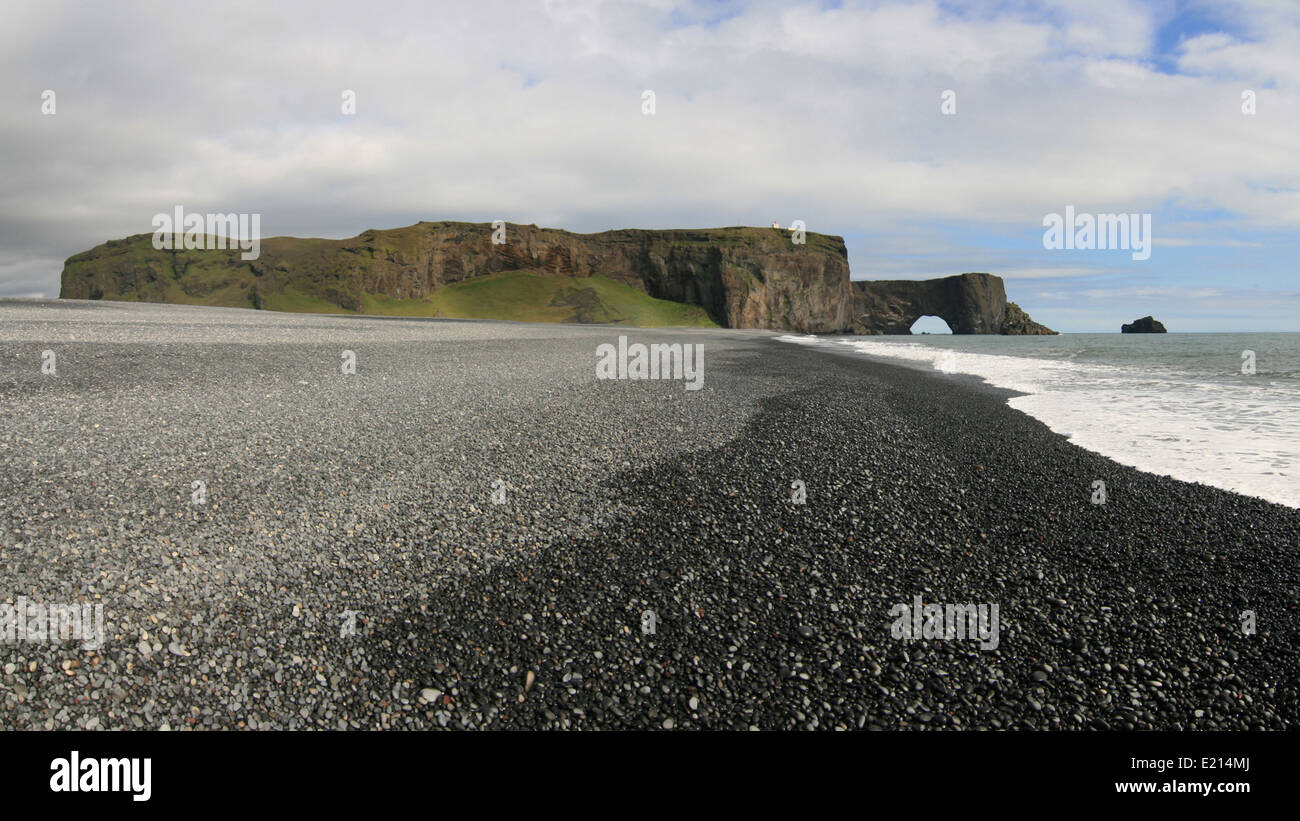 Promontorio di Dyrholaey e rock arch Lundadrangur da un nero nelle vicinanze spiaggia ghiaiosa. Foto Stock