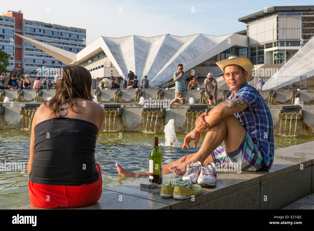 Giovane uomo e di altre persone in un momento di relax a Berlin Alexanderplatz nella luce della sera con una bottiglia di vino, Germania Foto Stock