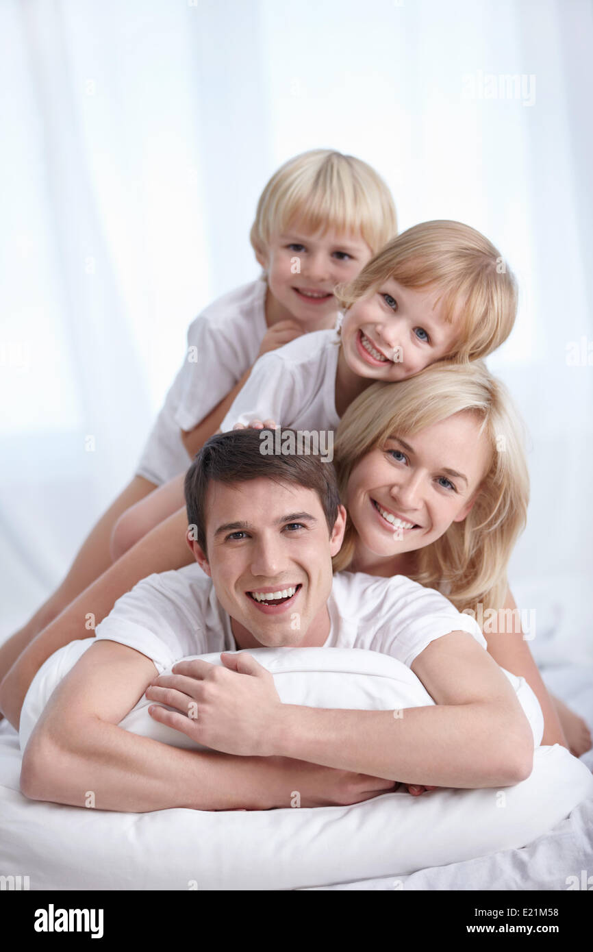 Una famiglia felice su un letto in camera da letto Foto Stock