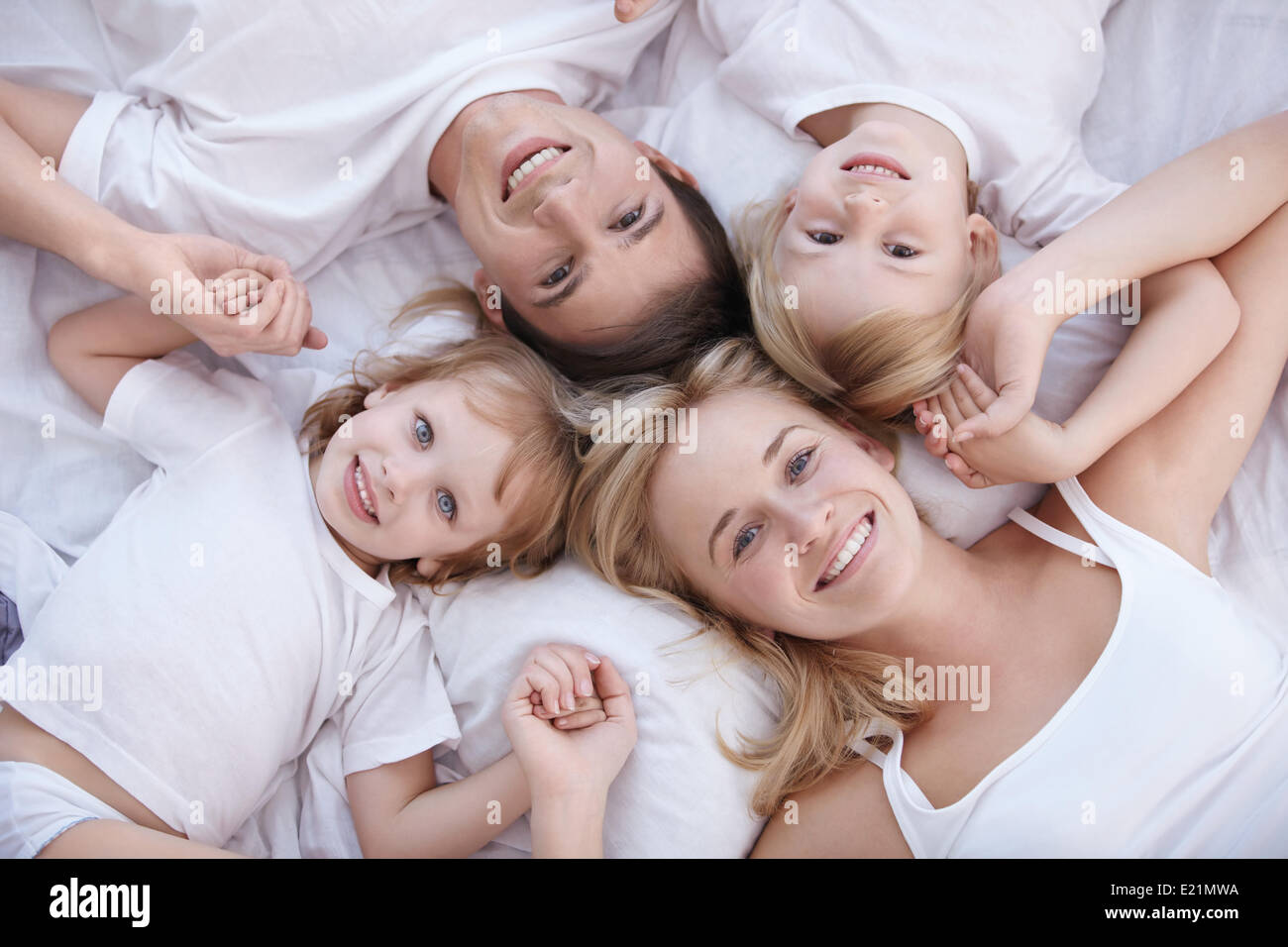 Famiglia sorridente giacciono su un letto bianco Foto Stock