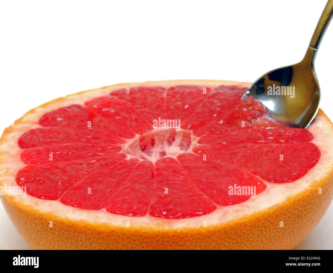 Una metà pompelmo con un cucchiaio Foto Stock