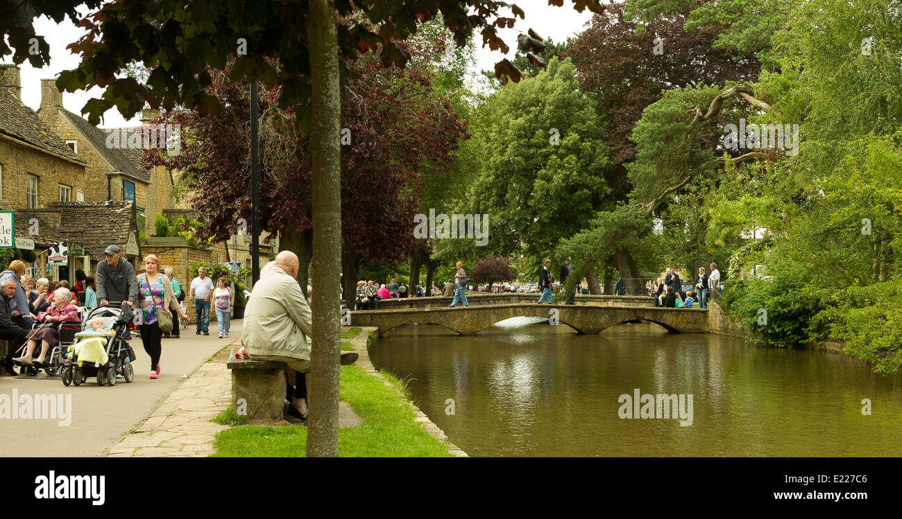 Visitatori e turisti affollano intorno al caffè, negozi e il Fiume Windrush a Bourton-on-the-acqua in Cotswolds Foto Stock