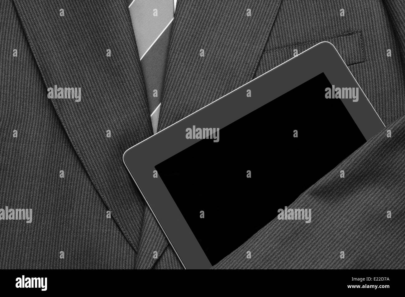 Primo piano di una camicia di business con una camicia bianca e cravatta con un braccio su un computer tablet. la tuta vuota è distesa e pronta Foto Stock