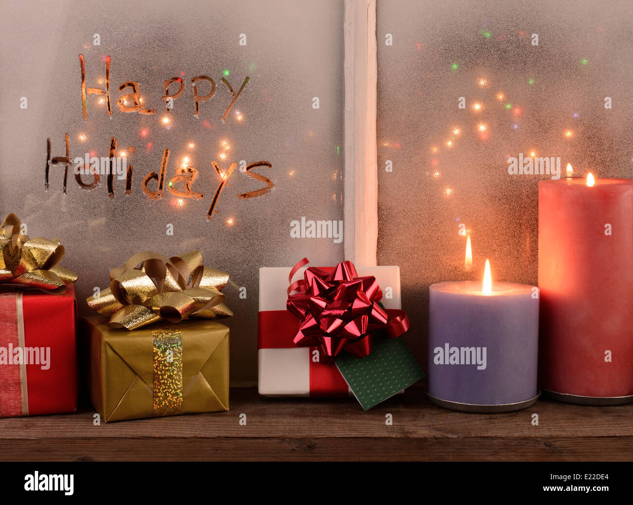 Vacanze felici scritto nel gelo di una finestra con le luci di Natale all'esterno della finestra. Foto Stock