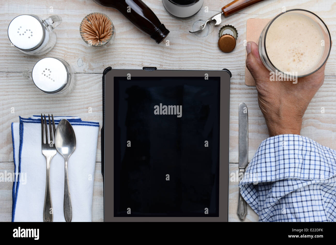Alta angolazione di un uomo con il suo bicchiere di birra in un ristorante tavola con una tabella del computer. Foto Stock