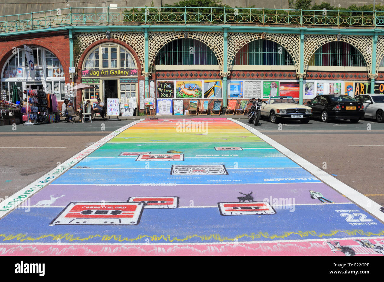 Madeira Drive, Brighton, Sussex. 13 giugno 2014. Il temporaneo rainbow crossing si estende attraverso la strada di artisti' trimestre di Madeira Drive. Si tratta di un pezzo di illustrazione non un attraversamento ufficiale ed è stato commissionato come parte delle celebrazioni per orgoglio LGBT mese. Se si desidera vedere essere veloce come sarà andato dal weekend! Credito: Julia Gavin/Alamy Live News Foto Stock