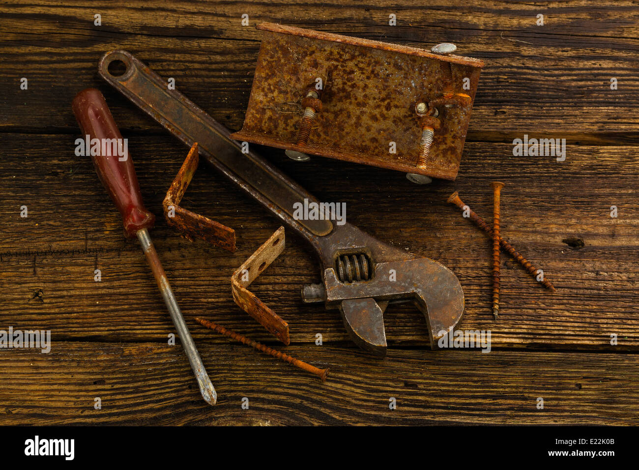 Angolo tiranti, viti, un cacciavite e una chiave regolabile su sfondo di legno Foto Stock