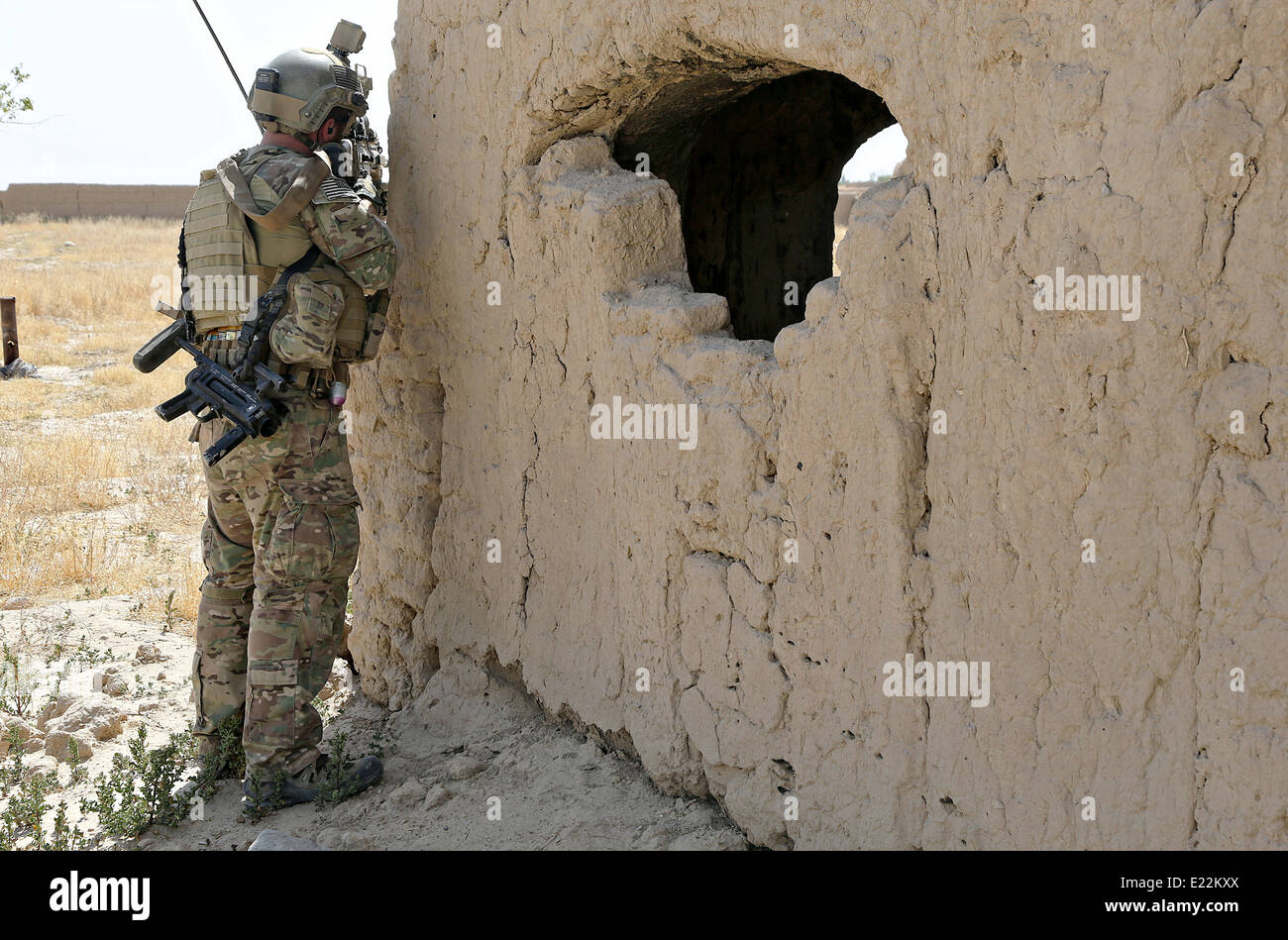 Un US Army Special Forces Soldier assegnato a Combined Joint Special Operations Task Force fornisce la sicurezza come esercito nazionale afghano delle forze speciali soldato con la terza le Operazioni Speciali Kandak cancellare un villaggio durante un'operazione Giugno 2, 2014 nel villaggio di Karezak, Maiwand distretto, provincia di Kandahar, Afghanistan. Foto Stock