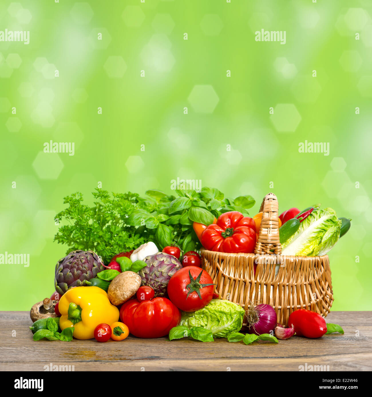 Le verdure e le erbe sul tavolo di legno sulla natura sfondo verde. crudo fresco ingredienti alimentari. Shopping basket Foto Stock