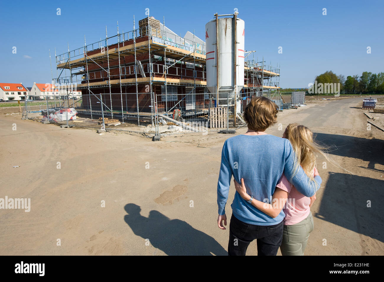 Coppia giovane cerca sul sito in costruzione come la loro nuova casa è in fase di costruzione Foto Stock