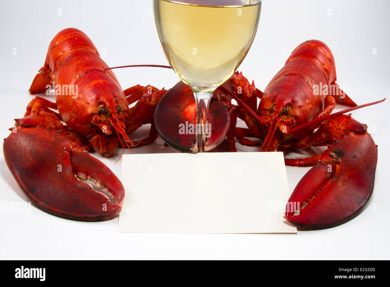 Due interi aragosta cotta con in mano un bicchiere di vino bianco e una ricetta o scheda del menu Foto Stock