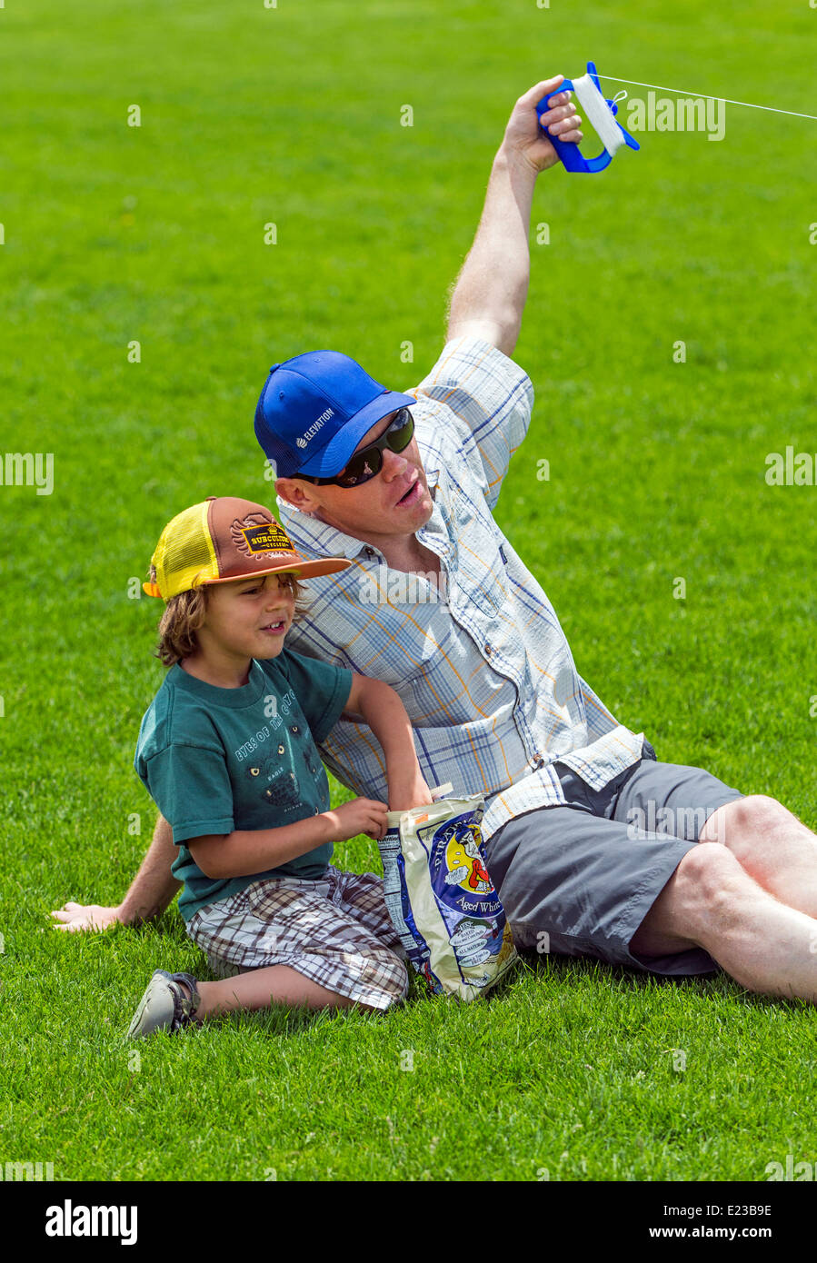 Padre e figlio giovane volare un aquilone su un campo erboso Foto Stock